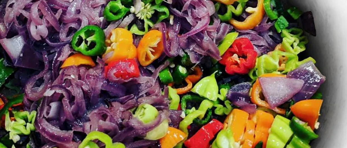 An iridescent array of chilies, onions, and garlic, slowly sweating over a low heat